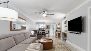 Ein modernes Wohnzimmer mit einer Couch, einem Couchtisch, einem Fernseher und einem Deckenventilator.