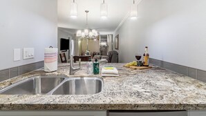 Eine Küche mit Granit Arbeitsplatten, Spüle aus Edelstahl und Pendelleuchten.
