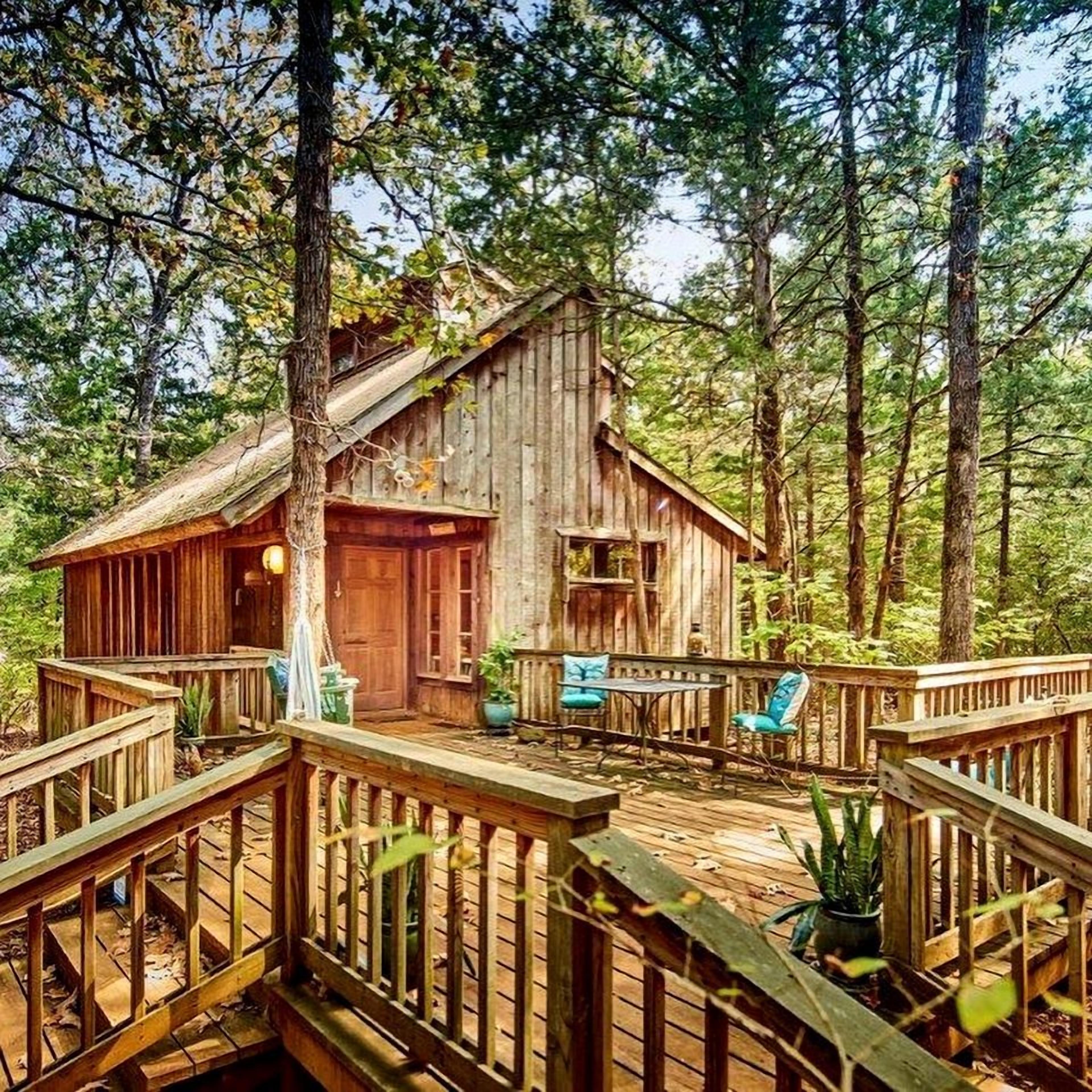 Un chalet rustique doté d’une terrasse en bois, entouré d’arbres.