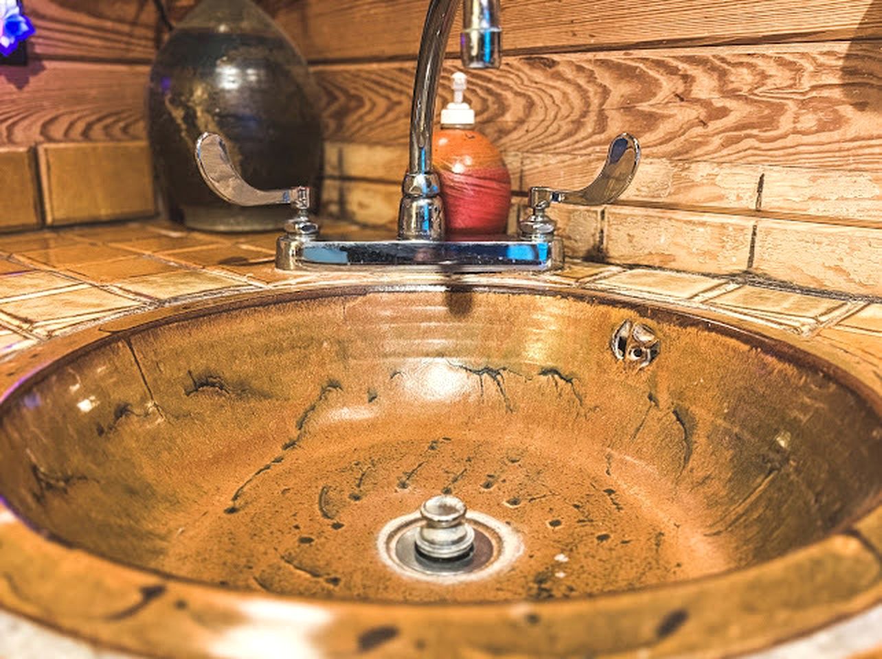 Ein Waschbecken aus Holz mit Wasserhahn und Seifenspender.