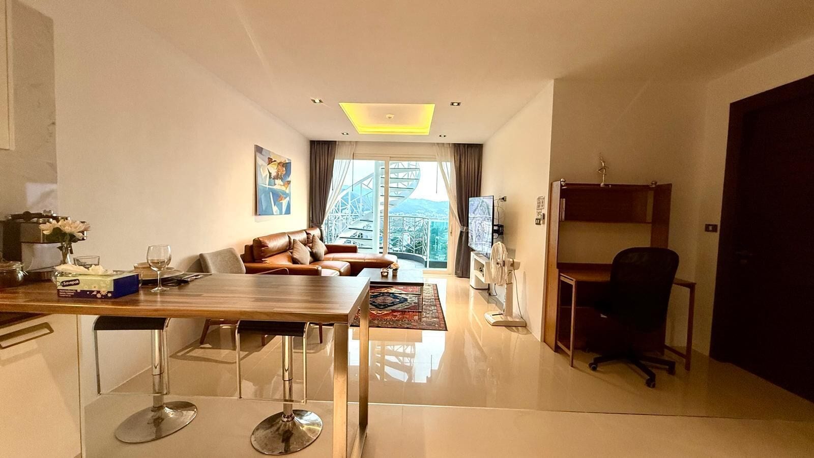 Ein modernes Wohnzimmer mit Essbereich, einer Couch, einem Fernseher und einem Balkon mit Blick.