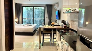 A modern hotel room with a bed, a dining area, and a kitchen. - Emerald Terrace Patong (Patong)