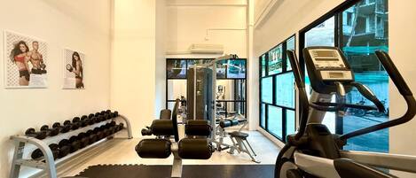 A gym with exercise equipment, dumbbells, and a treadmill.