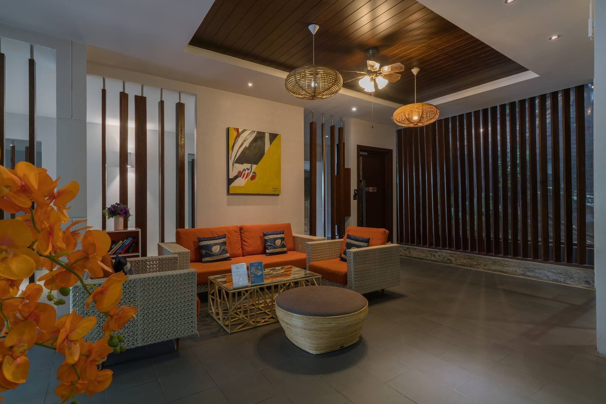 Un hall d’entrée moderne avec un canapé, des fauteuils, un pouf rond et un ventilateur de plafond.