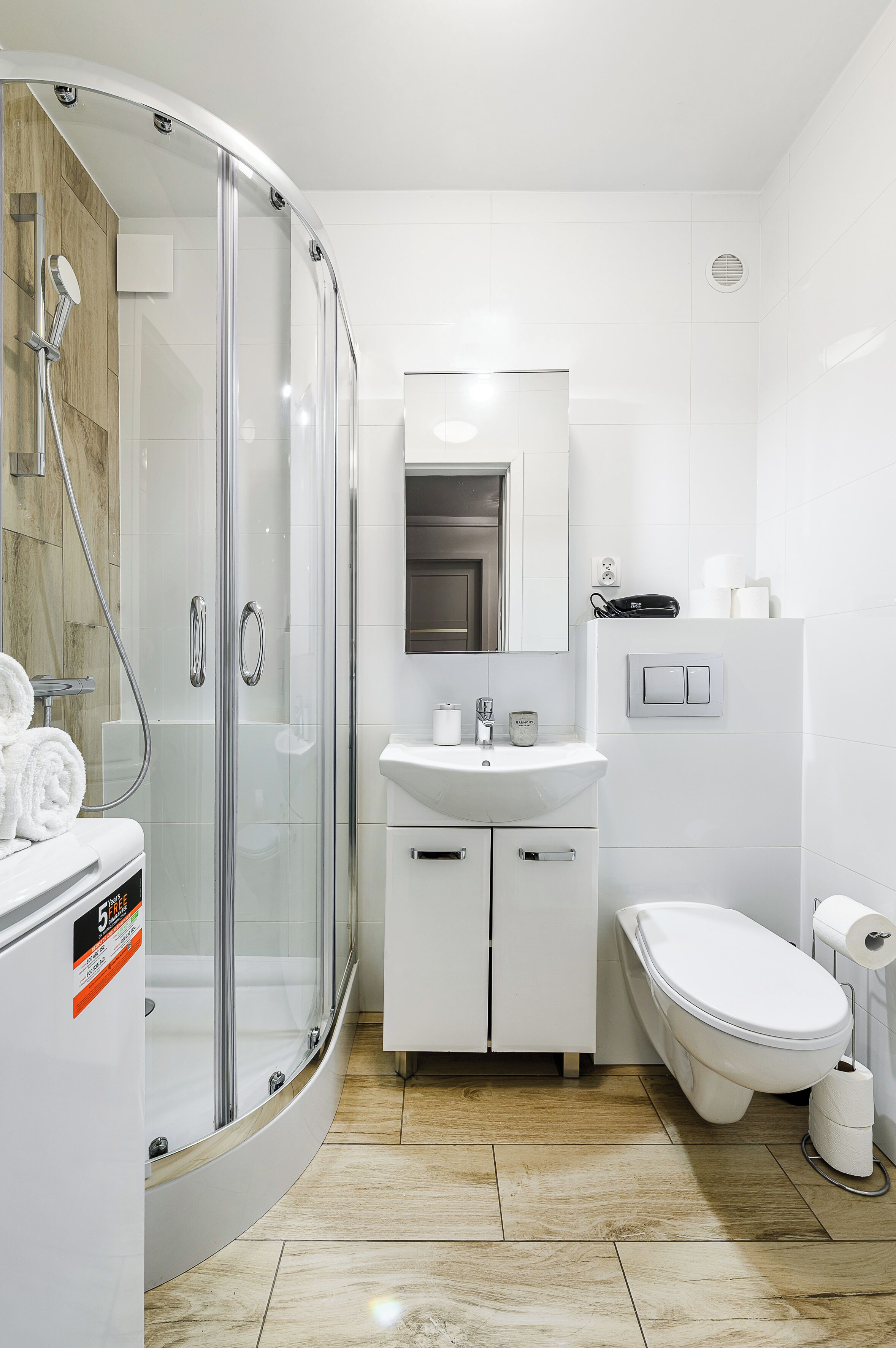 Une salle de bain moderne avec une douche à parois de verre, un lavabo blanc et des toilettes.