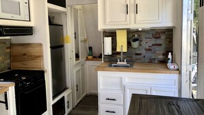 Uma cozinha compacta com armários brancos, um fogão, uma geladeira e uma pia.