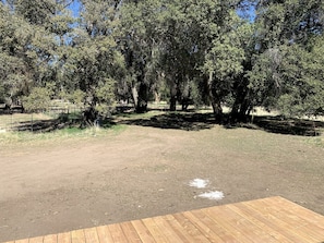 Un espace extérieur clos, doté d’une terrasse en bois et entouré d’arbres.