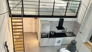 A compact kitchen with a dining area, a washing machine, and a small table with a lamp.