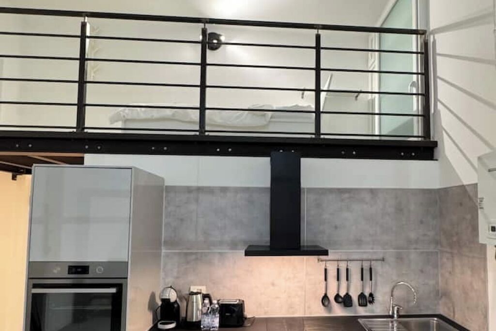 Een moderne keuken met een ingebouwde oven, een koffiezetapparaat en een hangende kruidenrek.