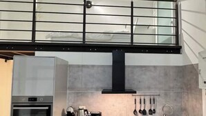 A modern kitchen with a built-in oven, a coffee maker, and a hanging pot rack.