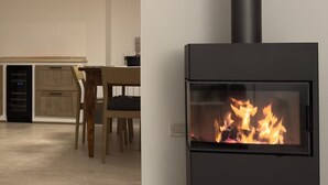 Una cucina moderna con stufa a legna, un'area pranzo con tavolo e sedie, e un pensile cucina.