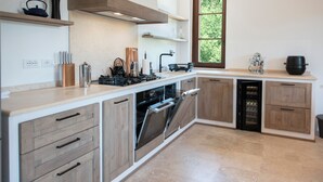 Una cucina moderna con mobili in legno, forno integrato e una finestra vista verde.