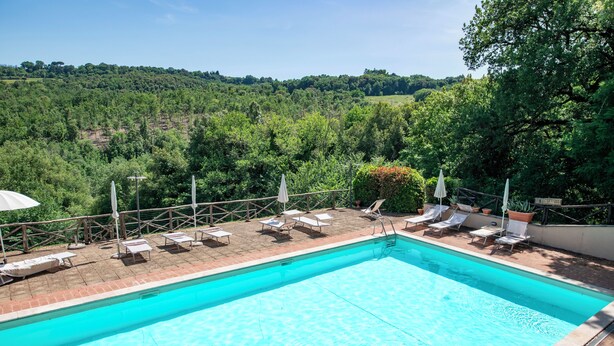 Una piscina rettangolare con acqua cristallina e bordo in mattoni. Lungo il bordo piscina, ci sono lettini e ombrelloni.