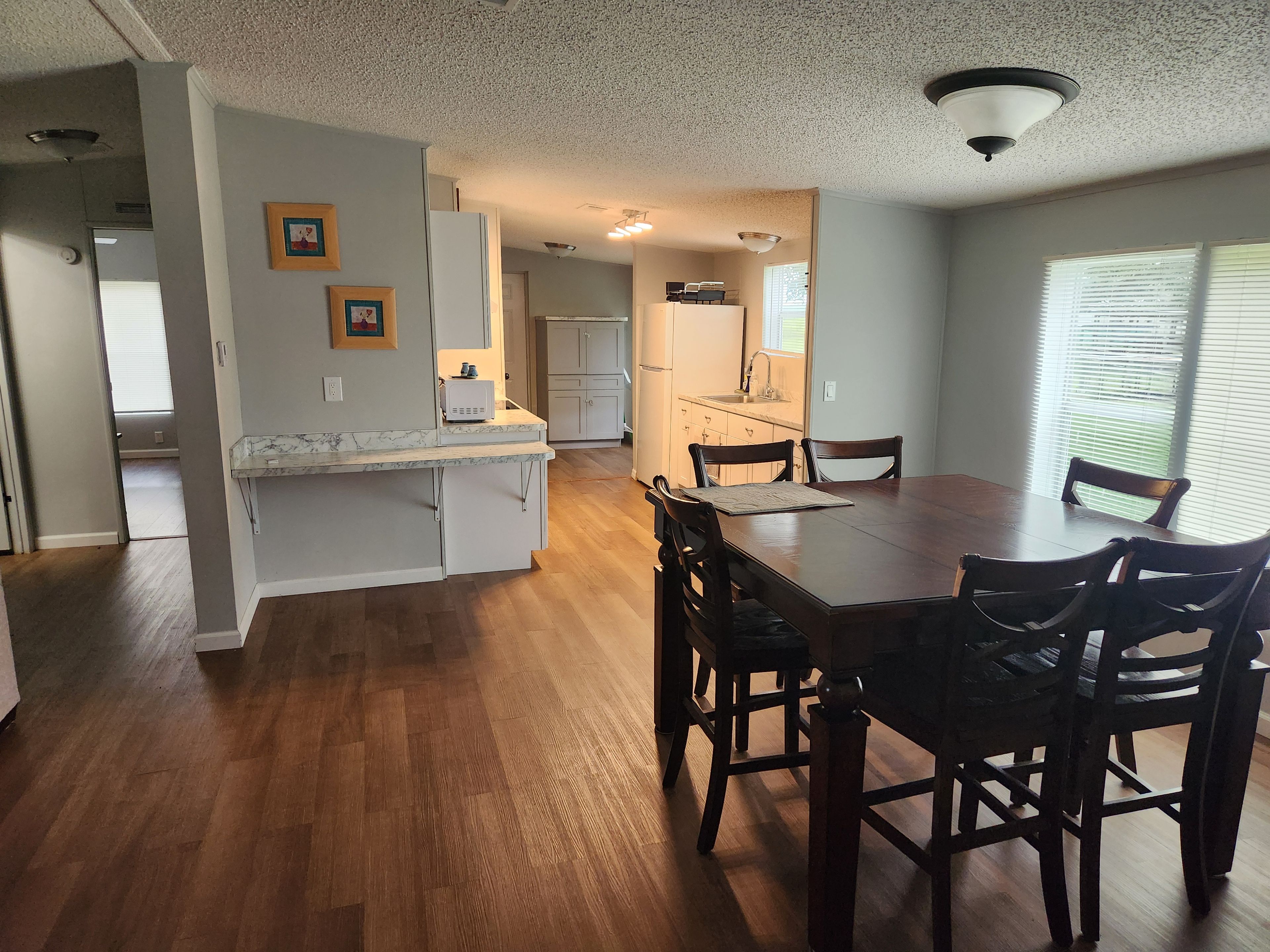 Una cocina amplia con comedor, suelo de madera y vista al salón contiguo.