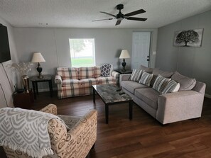 A living room with a sofa, armchairs, a coffee table, and two lamps.