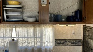 Eine Küche mit einem Holzkasten, einem Durchlauferhitzer und einem Fenster mit Vorhang.
