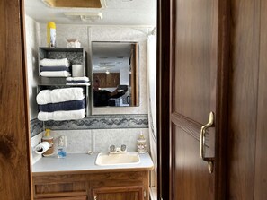 A bathroom with a wooden vanity, a sink, a mirror, and a towel rack. - Shabby Chic Warner Springs Rental at a Ranch Ideal for Glamping in California (Warner Springs)