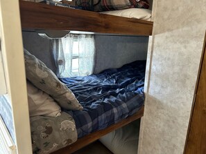 Una cama litera con una almohada estampada y una manta azul.