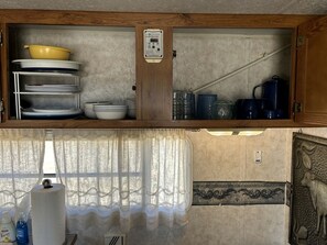 Una cocina con un armario de madera, calentador de agua y una ventana con cortina.
