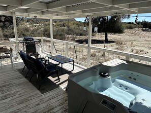 A covered outdoor deck with a hot tub, seating area, and a view of the surrounding landscape. - Shabby Chic Warner Springs Rental at a Ranch Ideal for Glamping in California (Warner Springs)