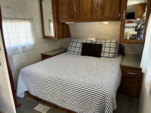 A bedroom with a bed, wooden cabinets, a mirror, and a small bedside table. - Shabby Chic Warner Springs Rental at a Ranch Ideal for Glamping in California (Warner Springs)