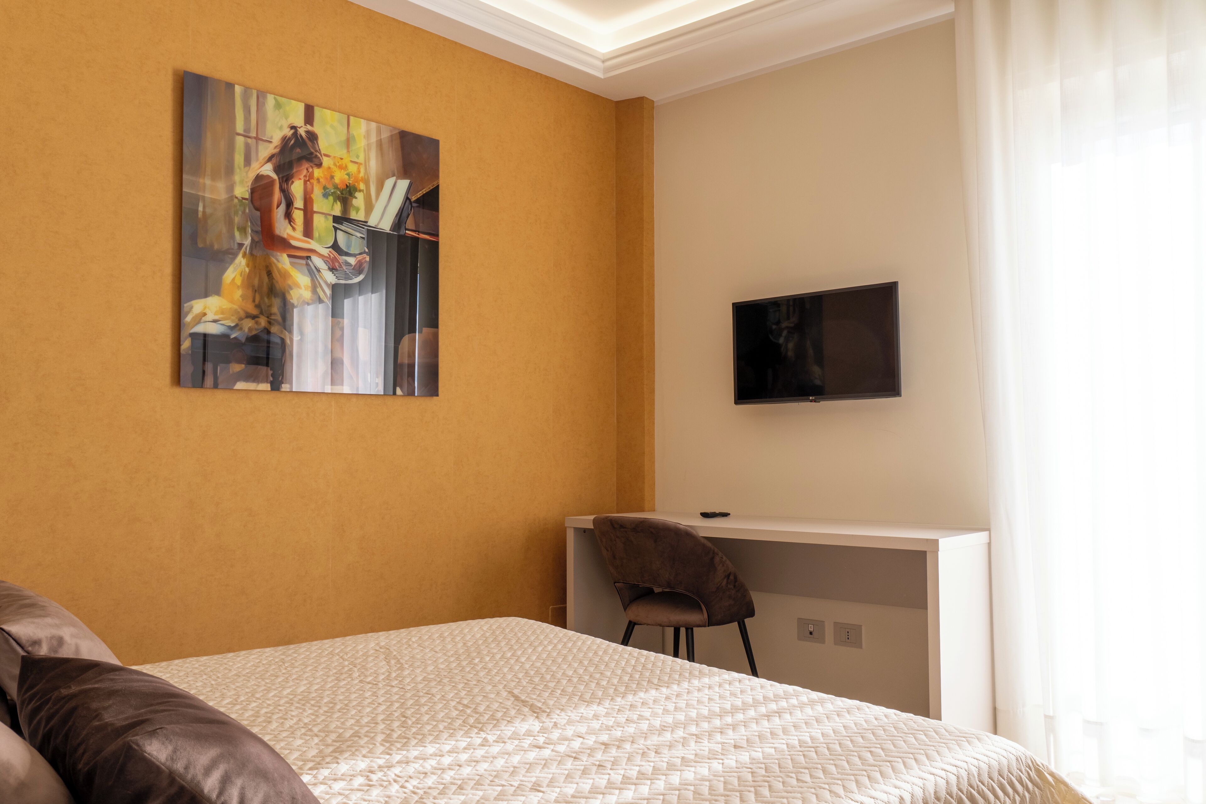 Ein Hotelzimmer mit Bett, Schreibtisch, Stuhl, Fernseher und einem Gemälde an der Wand.