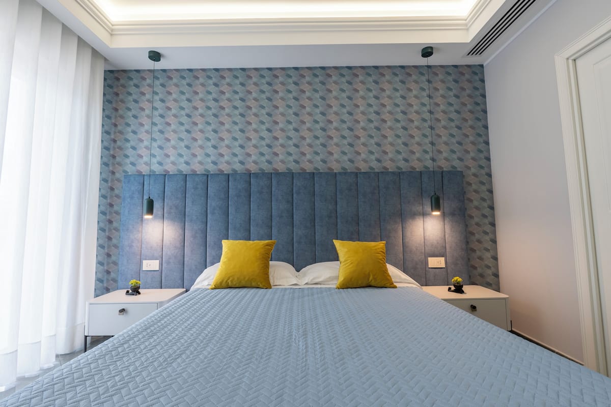 Un dormitorio moderno con una cama grande, dos mesitas de noche y una pared con diseño.