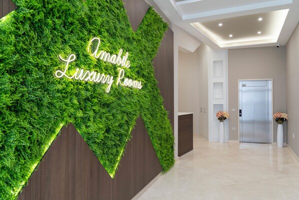 Un hall con una pared verde y un letrero que dice "Amabile Luxury Rooms".