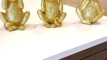 Three golden monkey figurines on a white surface.