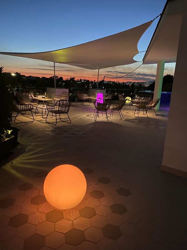 An outdoor patio with hexagonal flooring, a large illuminated sphere, and multiple seating areas under a canopy. - Amabile Luxury Rooms (Sant'Antonio Abate)