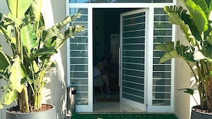 Una entrada moderna con puerta de cristal, plantas en macetas y suelo de piedra con diseño.