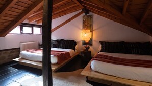 Een knus slaapkamer op zolder met twee bedden, een houten plafond, een radiator en een wandlamp.