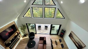 Ein geräumiges Loft mit großem Fernseher, einer gemütlichen Sitzecke und einem Balkon mit Gartenmöbeln.
