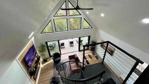 Ein Zimmer mit hohen Decken, einem großen Oberlicht, einem Deckenventilator und Blick auf eine Terrasse.