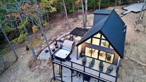 Eine moderne Holzhütte mit Terrasse, Sitzgelegenheiten im Freien und einem Whirlpool.