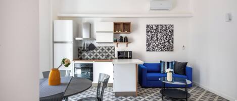 A compact living space with a kitchenette, dining area, and a blue sofa.