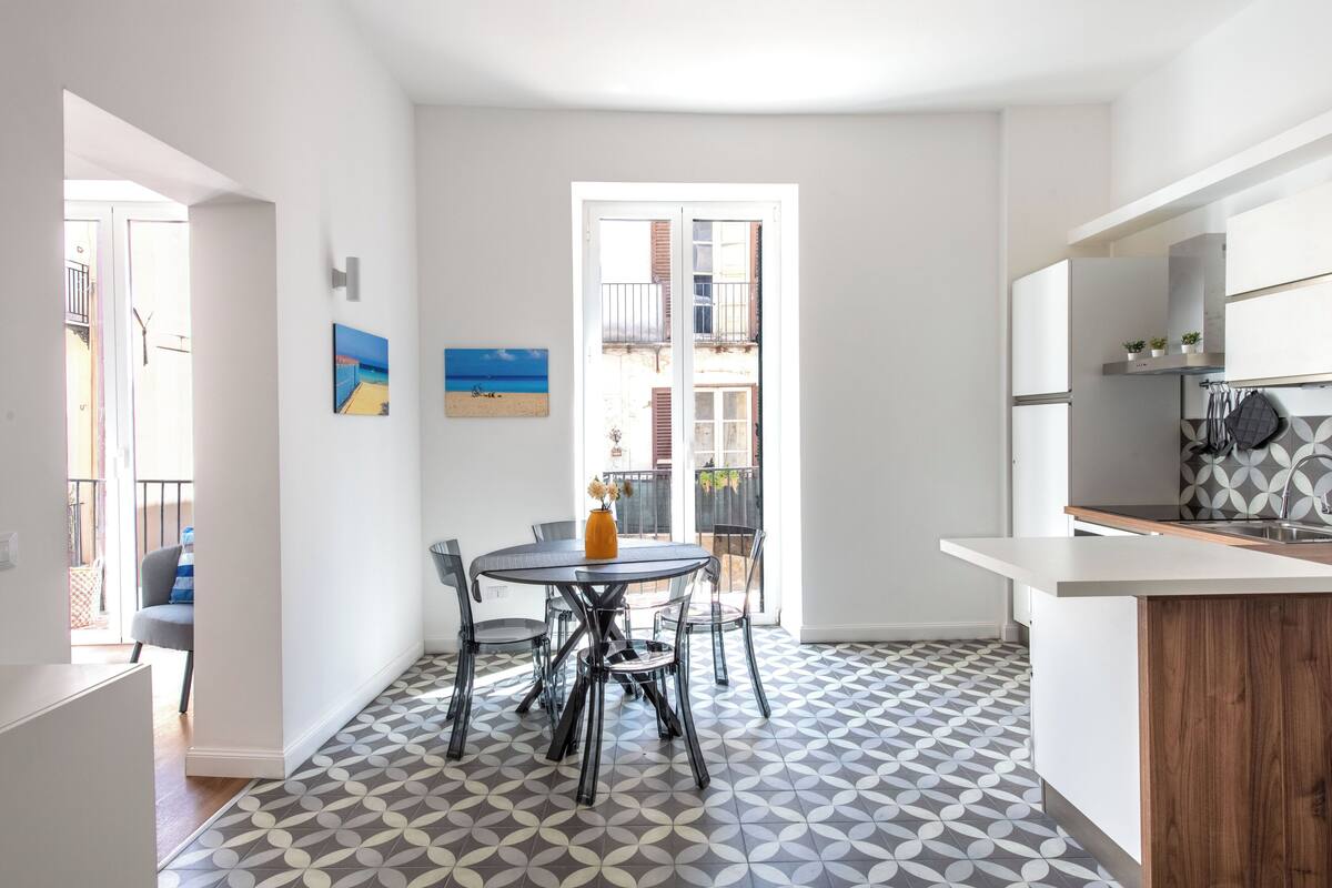 Une cuisine moderne dotée d’un îlot central, d’un coin repas avec une table ronde et des chaises, et d’un sol à motifs.