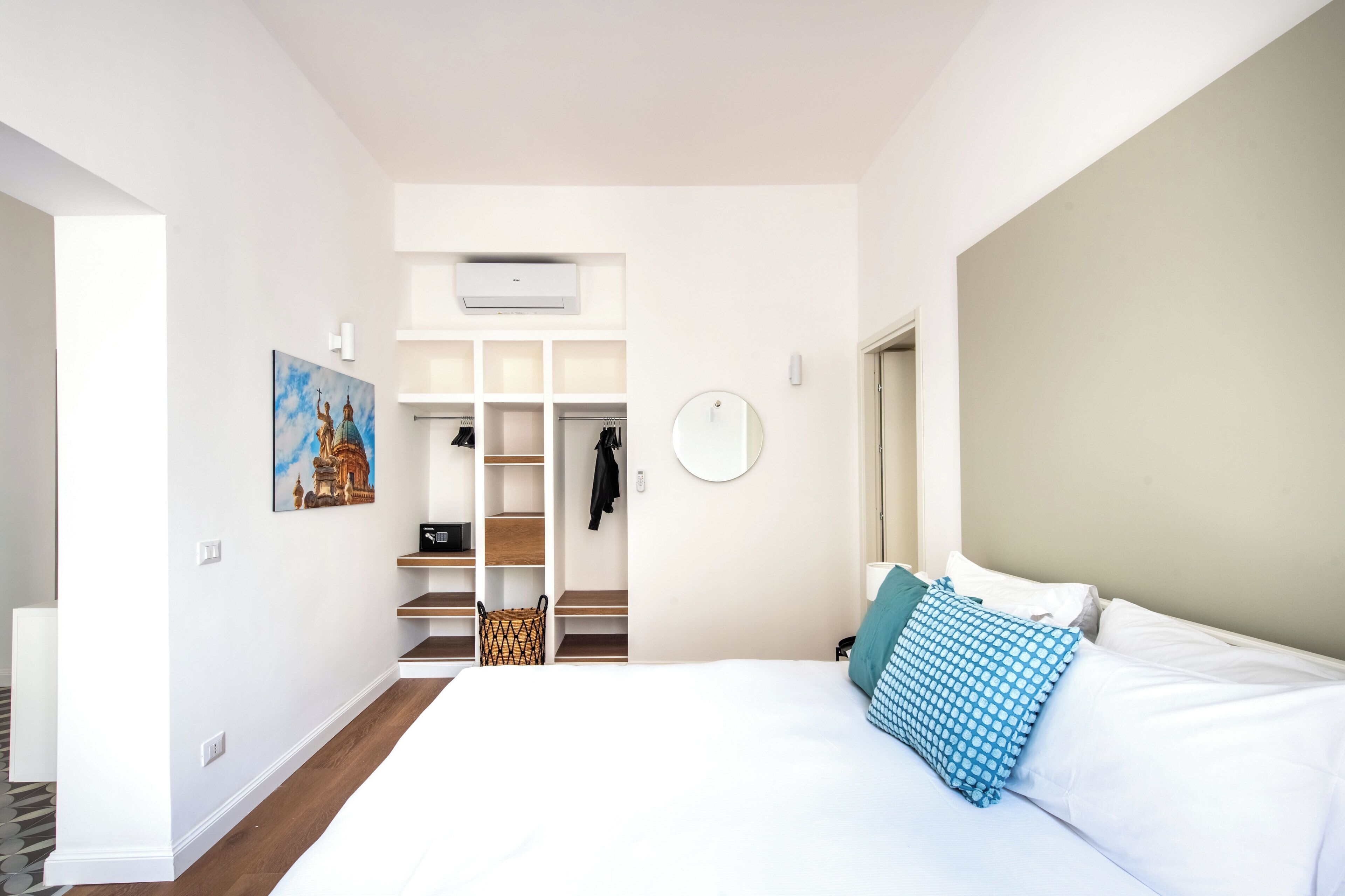 A modern hotel room with a large bed, a walk-in closet, and a painting on the wall.