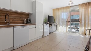 Een moderne keuken met witte kasten, een vaatwasser en een houten spatwand.