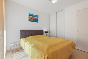 A bedroom with a bed, a small round table, a painting on the wall, and a wardrobe.