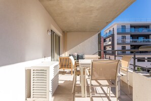 A balcony with a table and chairs, a sofa, and a window.
