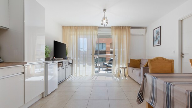 Een moderne hotelkamer met een keuken, een eethoek, een bed en een balkon met uitzicht.