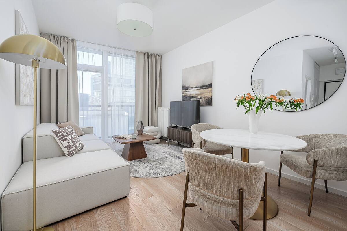 Un salon moderne avec un canapé, des fauteuils, une table basse, un téléviseur et un grand miroir.
