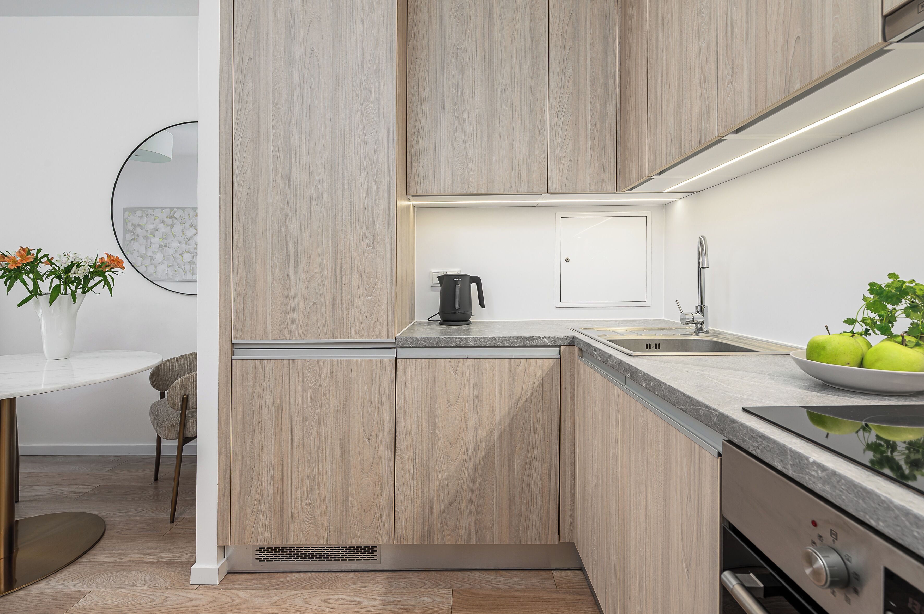 A modern kitchen with wooden cabinets, a built-in stove, and a sink.