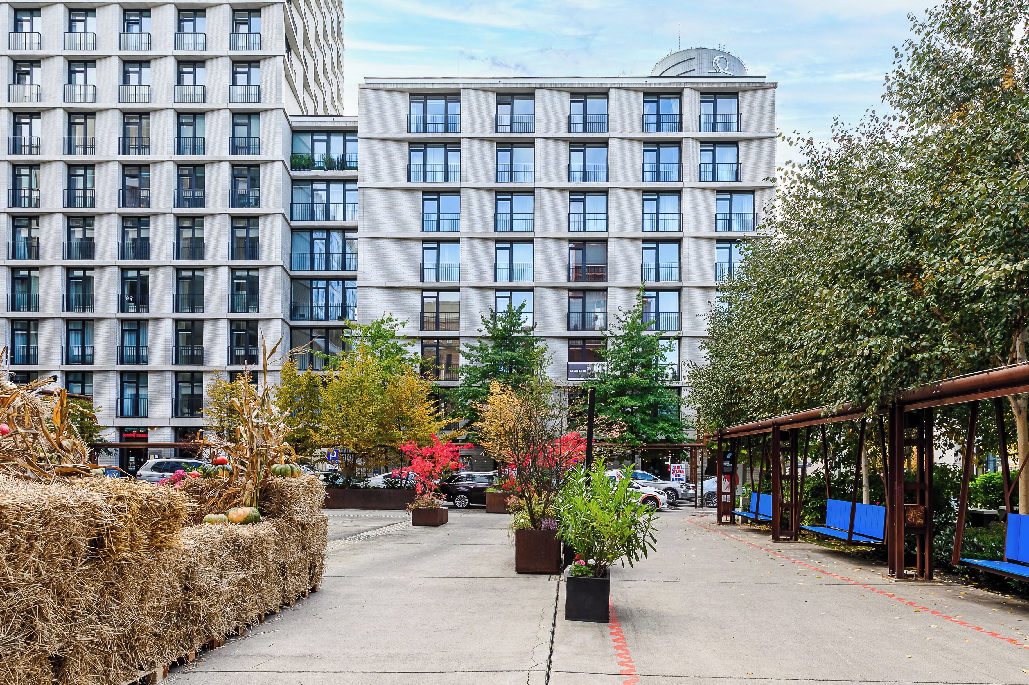 A modern hotel with a central courtyard, featuring a seating area with benches and potted plants.