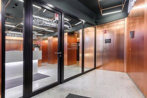 An interior corridor with glass doors, a reception area, and an elevator. - ShortStayPoland Browary Warszawskie  (Warsaw)
