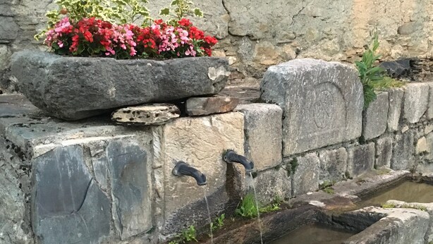 A stone water feature with a flower bed, a stone wall, and a small pond. - Charming Mountain House in the Heart of the Pyrenees (Garin)