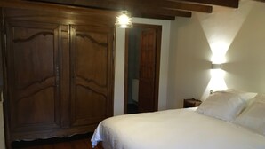 A bedroom with a wooden wardrobe, a bed with white linens, and a nightstand with a lamp. - Charming Mountain House in the Heart of the Pyrenees (Garin)