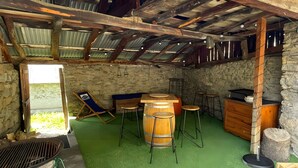 A rustic outdoor area with a wooden barrel, stools, a grill, and a stone wall. - Charming Mountain House in the Heart of the Pyrenees (Garin)