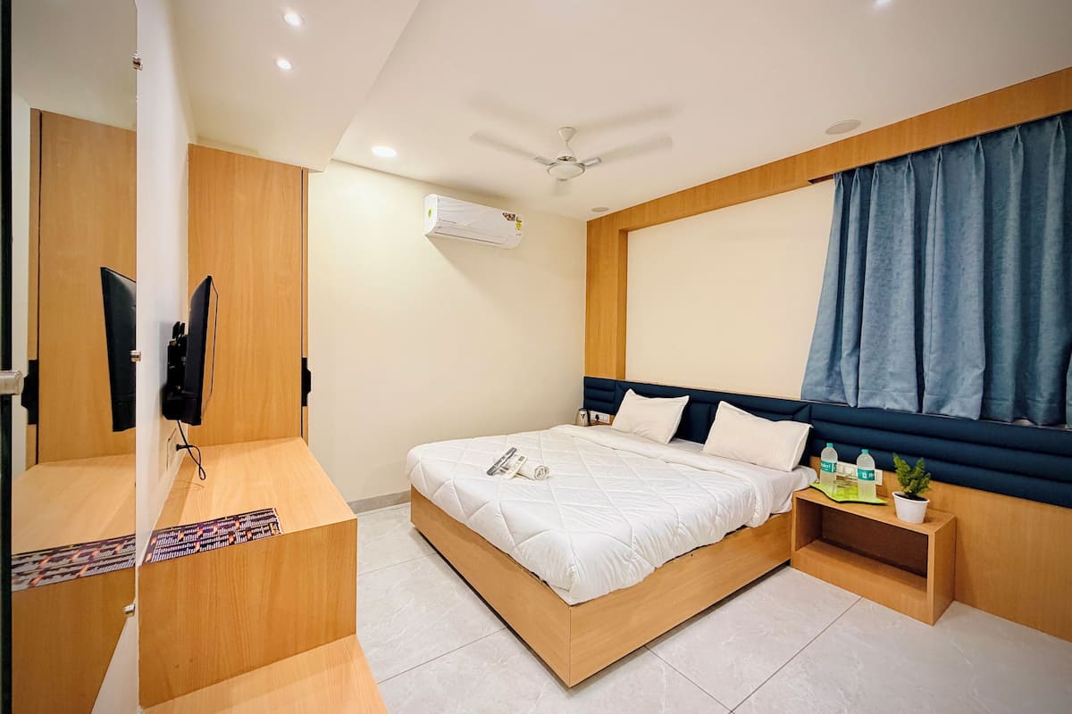 A modern bedroom with a wooden bed frame, a bedside table with a plant, and a ceiling fan.